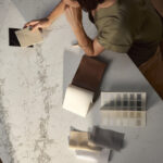 Countertop and fabric samples on top of a Caesarstone ICON countertop of white Celestial Sky advanced fusion with a veiny overlay of gray, brown, and green undertones.