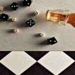 Dice and a spilled drink on a table of white Ocean Foam quartz with specks of gray.