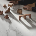 Wooden blocks sit atop an advanced fusion countertop of Calacatta Nobella, a silica-free* quartz alternative, with light-gray veins, accented by warm copper tints.