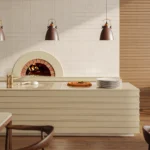 Caesarstone ICON 4201 Organic Dune beige surface featured in a modern restaurant interior with a pizza oven island countertop and warm wood accents